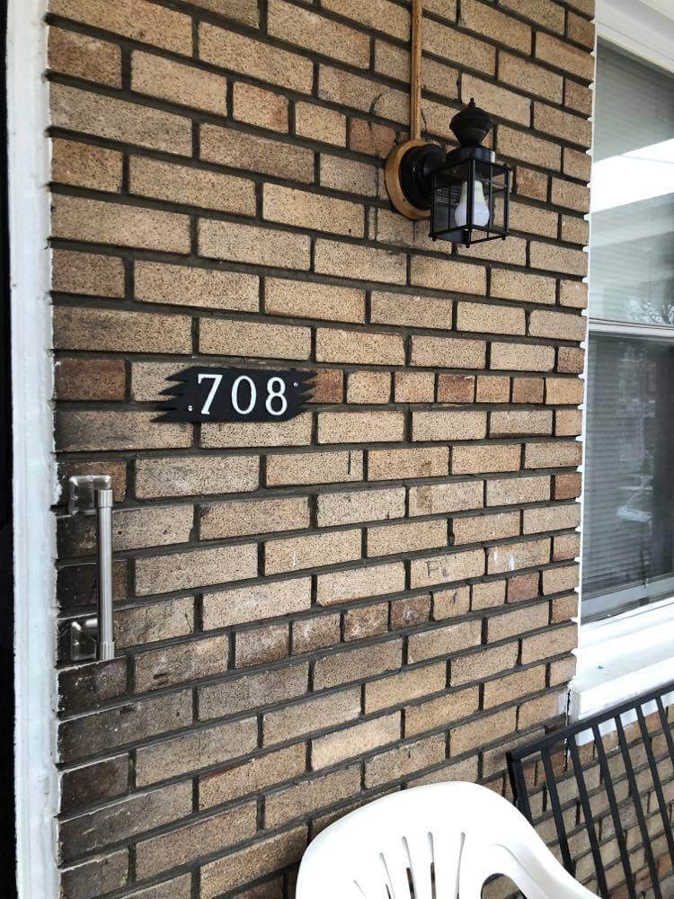 An image showing "708" address of a home against a brick wall