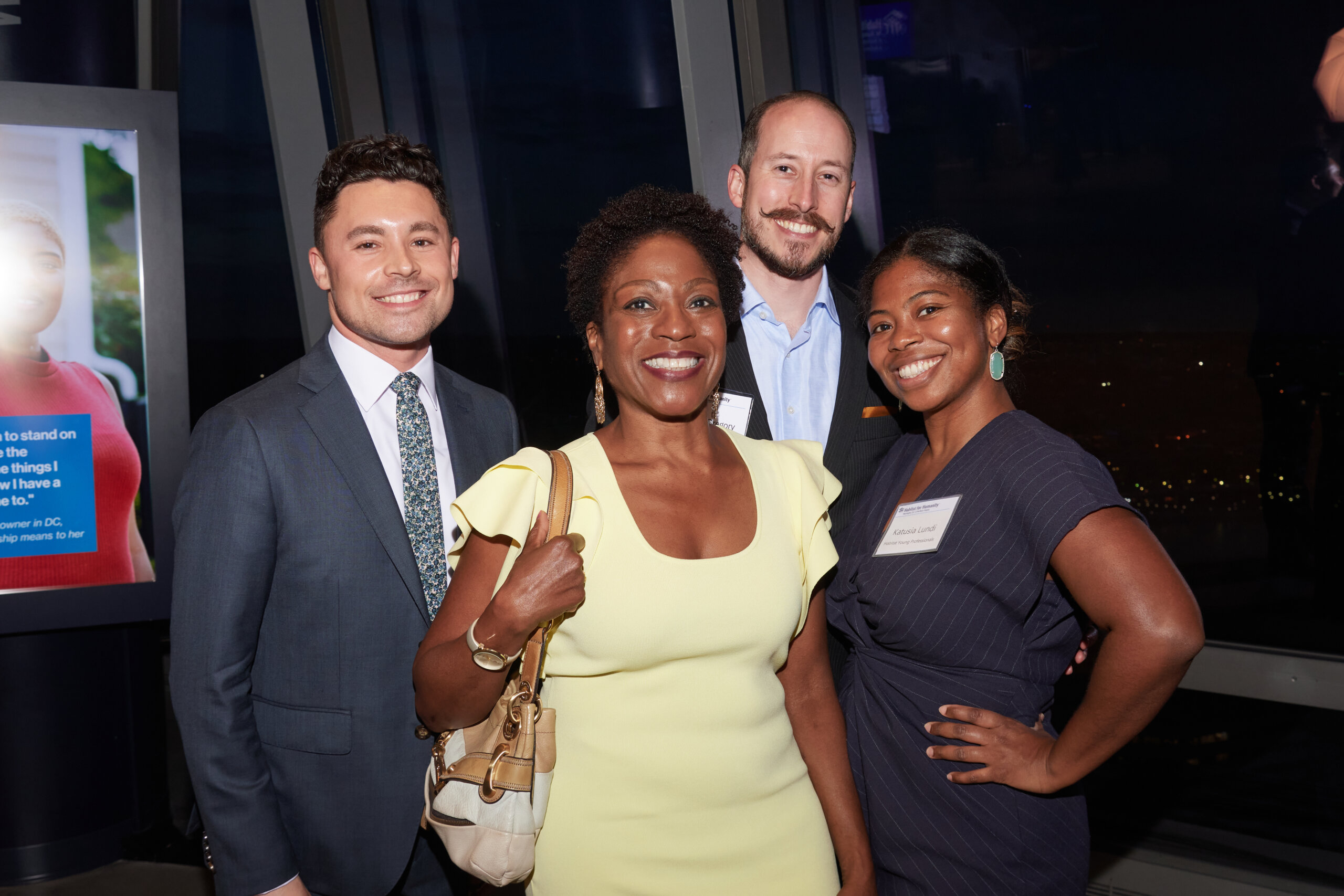 Group of four people dressed in business attire smiling at the camera