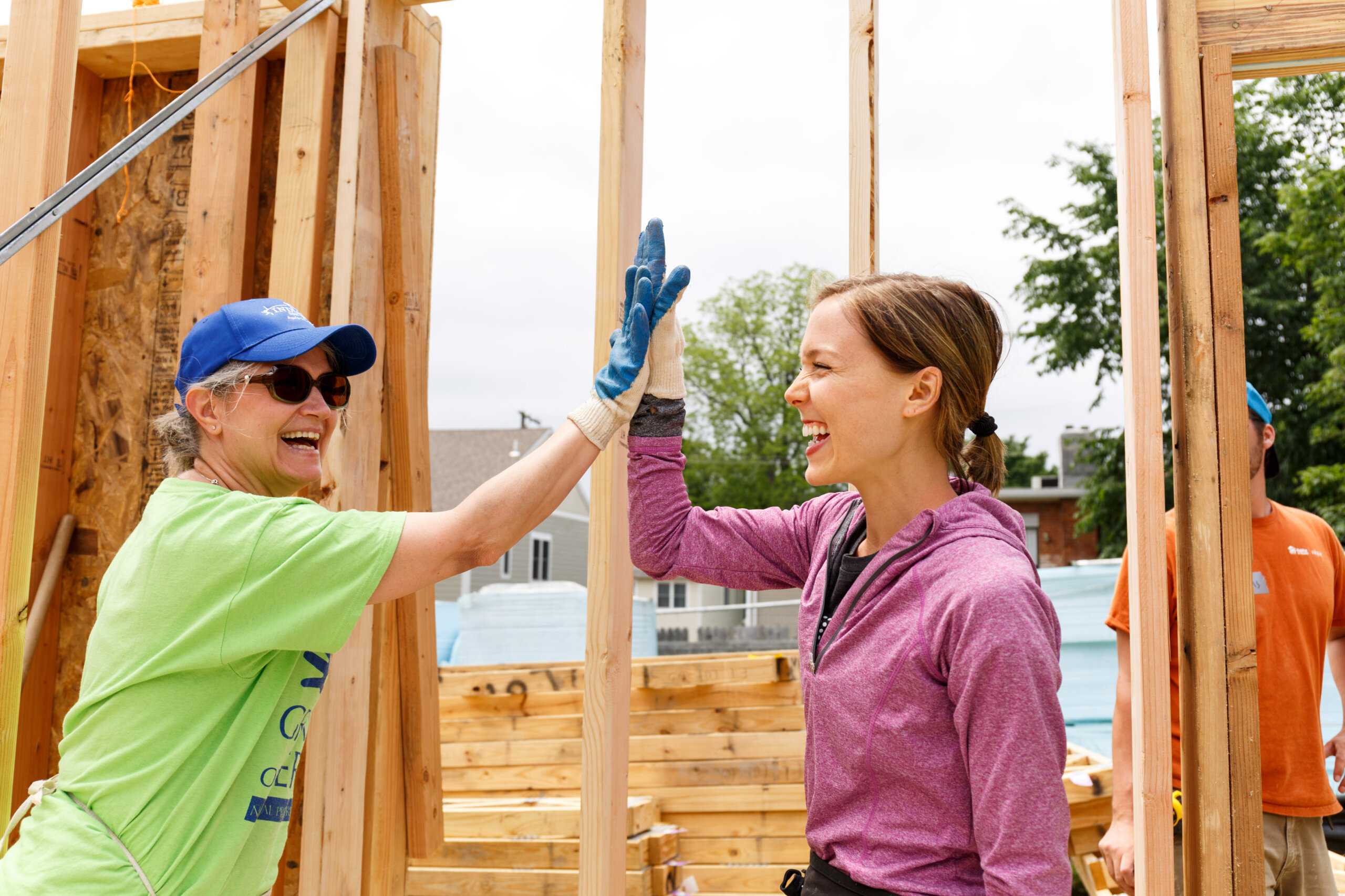 Two women smiling in front of wooden beams high-fiving 