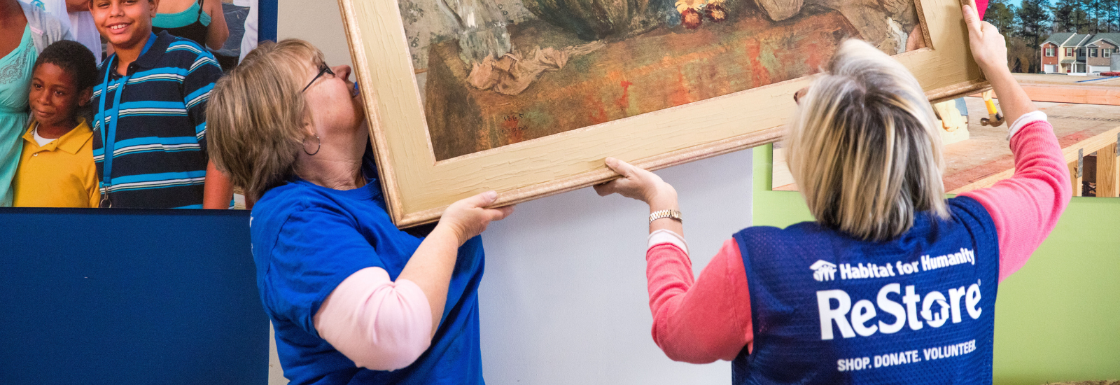 Two women hanging a picture frame on the wall