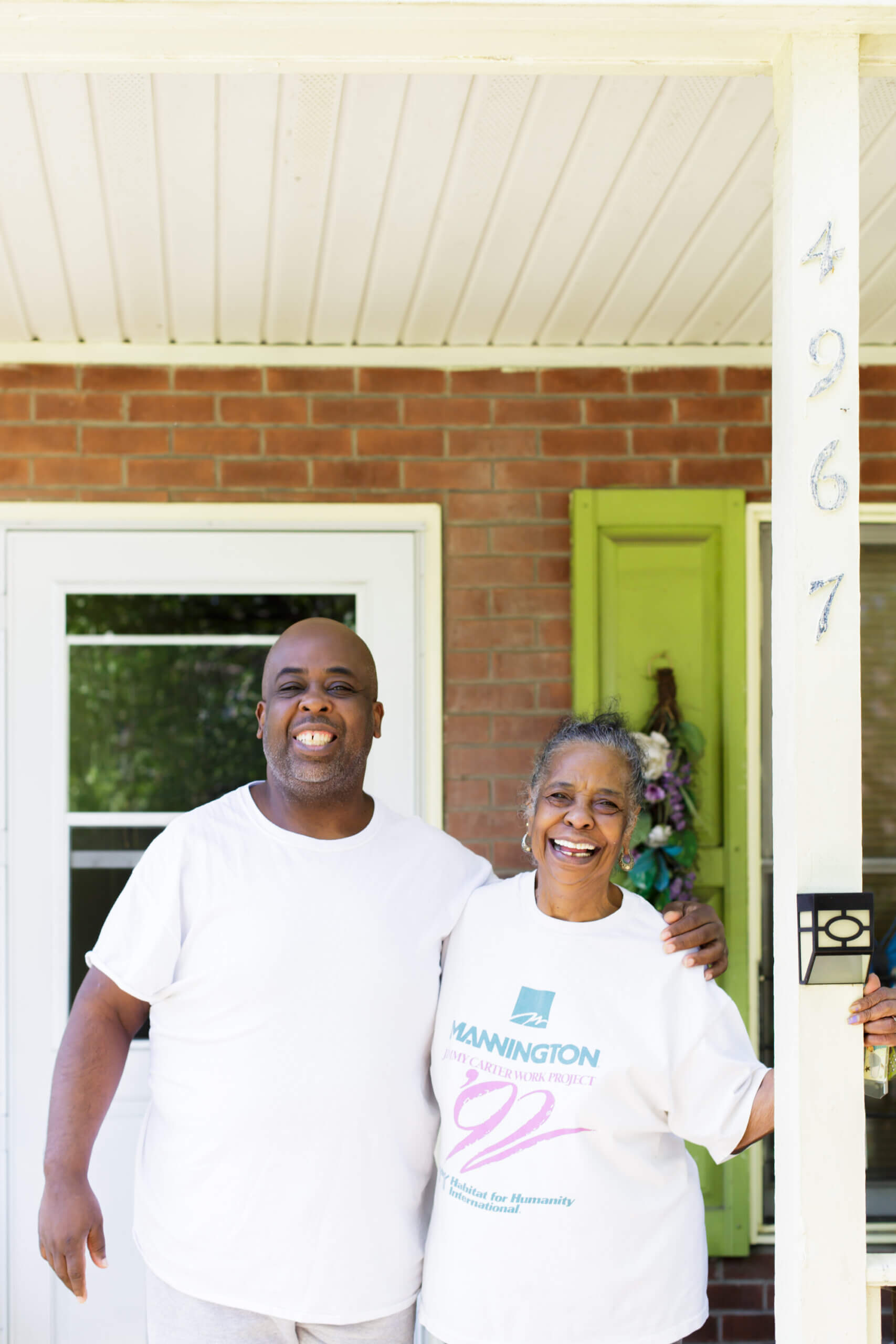 a man and women smiling and embracing in front of a home