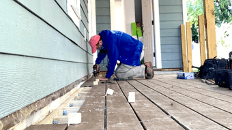 A person crouched down repairing floorboards